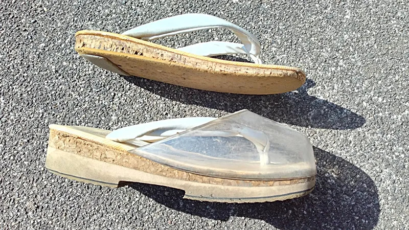 Side view of traditional monk sandals next to rain-version sandals with thicker soles and clear toe protection.